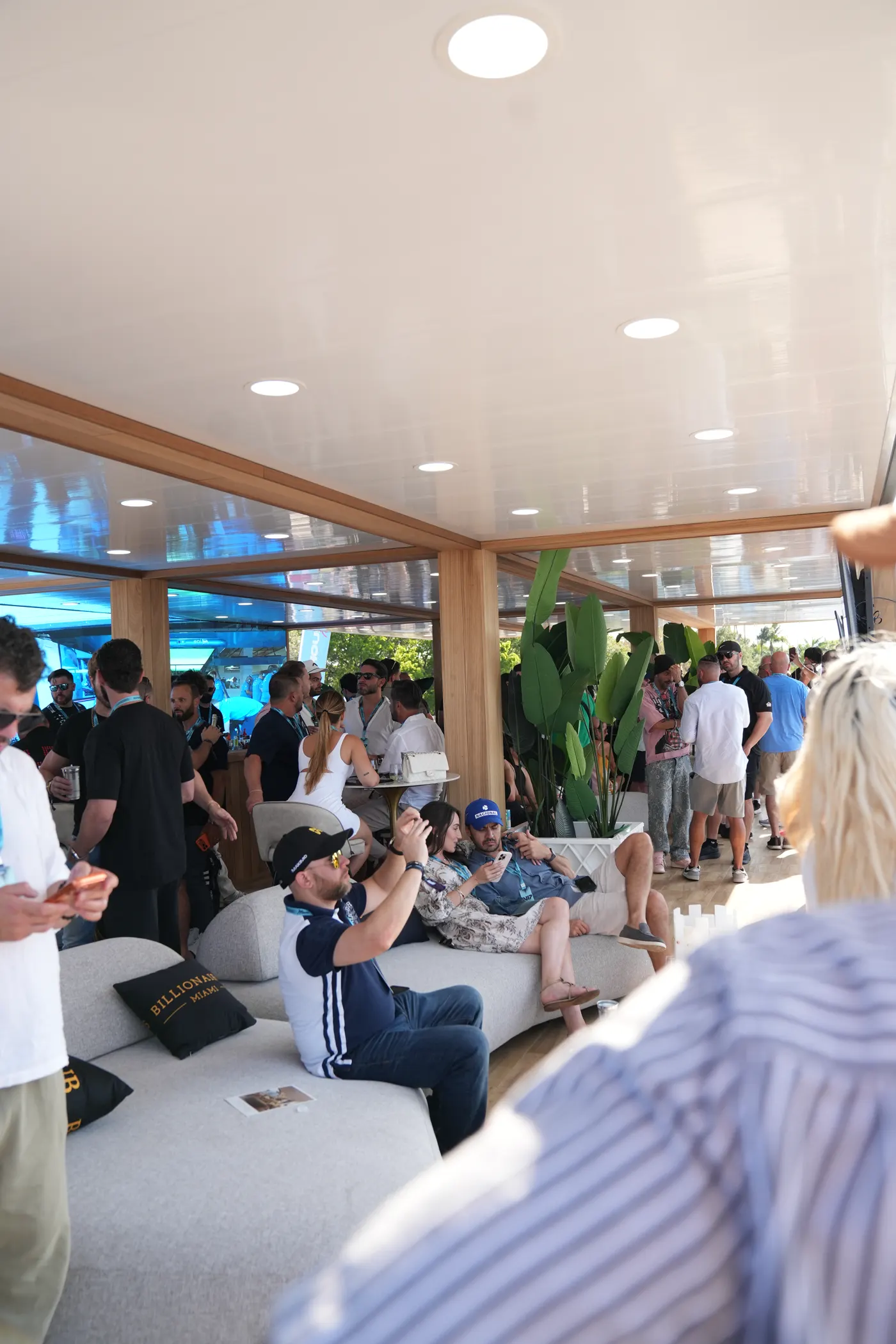 The GRID House suite interior, guests seated and standing, the circuit beyond the glass