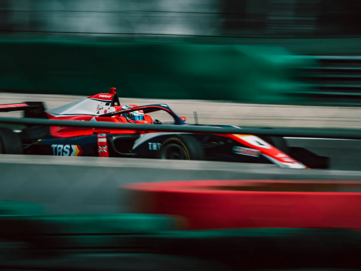 A single-seater race car at speed on a circuit, motion-blurred