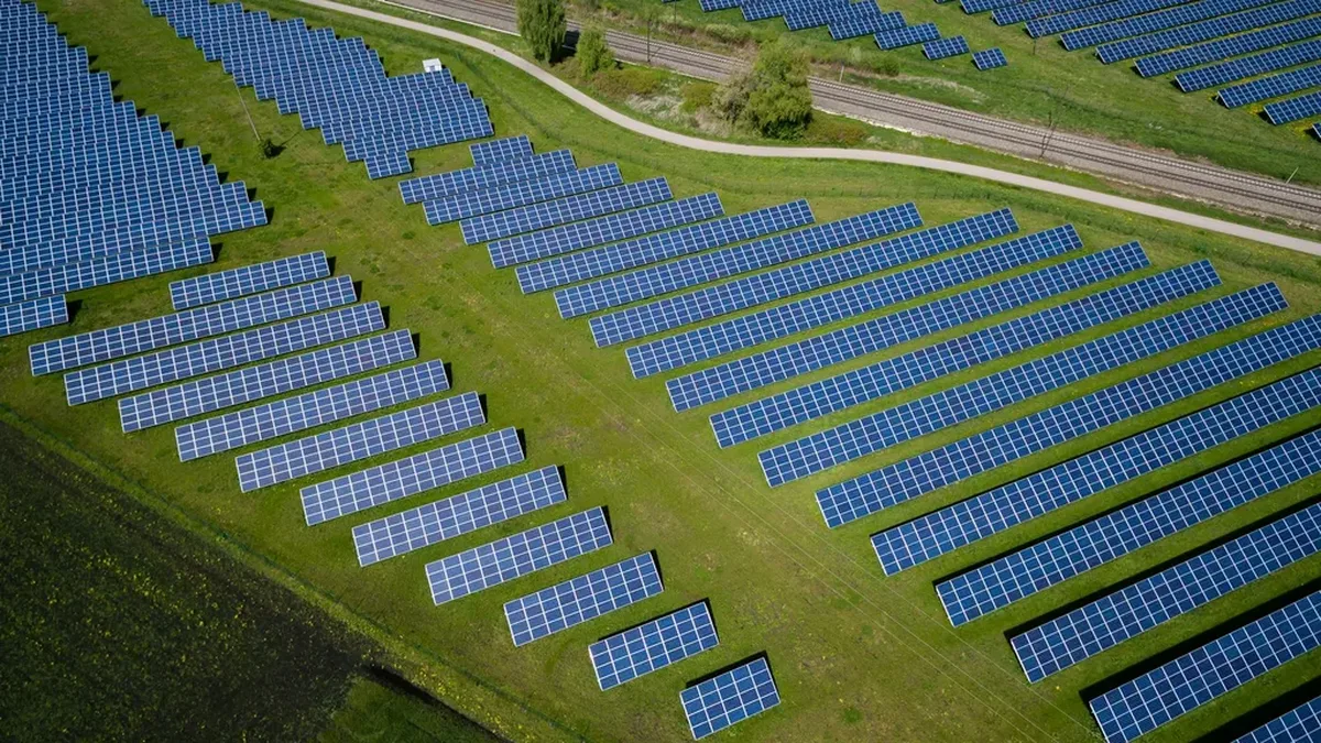 Aerial view of a solar panel farm on green fields (illustrative photograph).